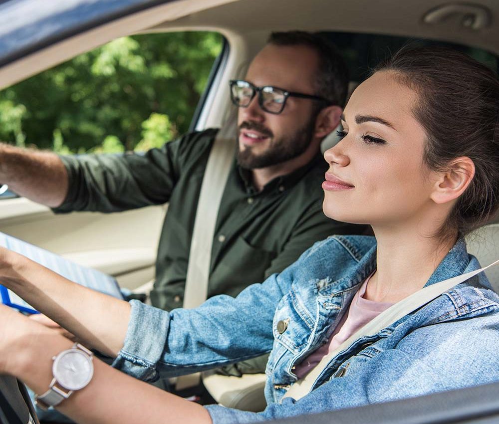 cheerful-student-and-teacher-in-car-at-driving-tes-8WUZ9MG.jpg